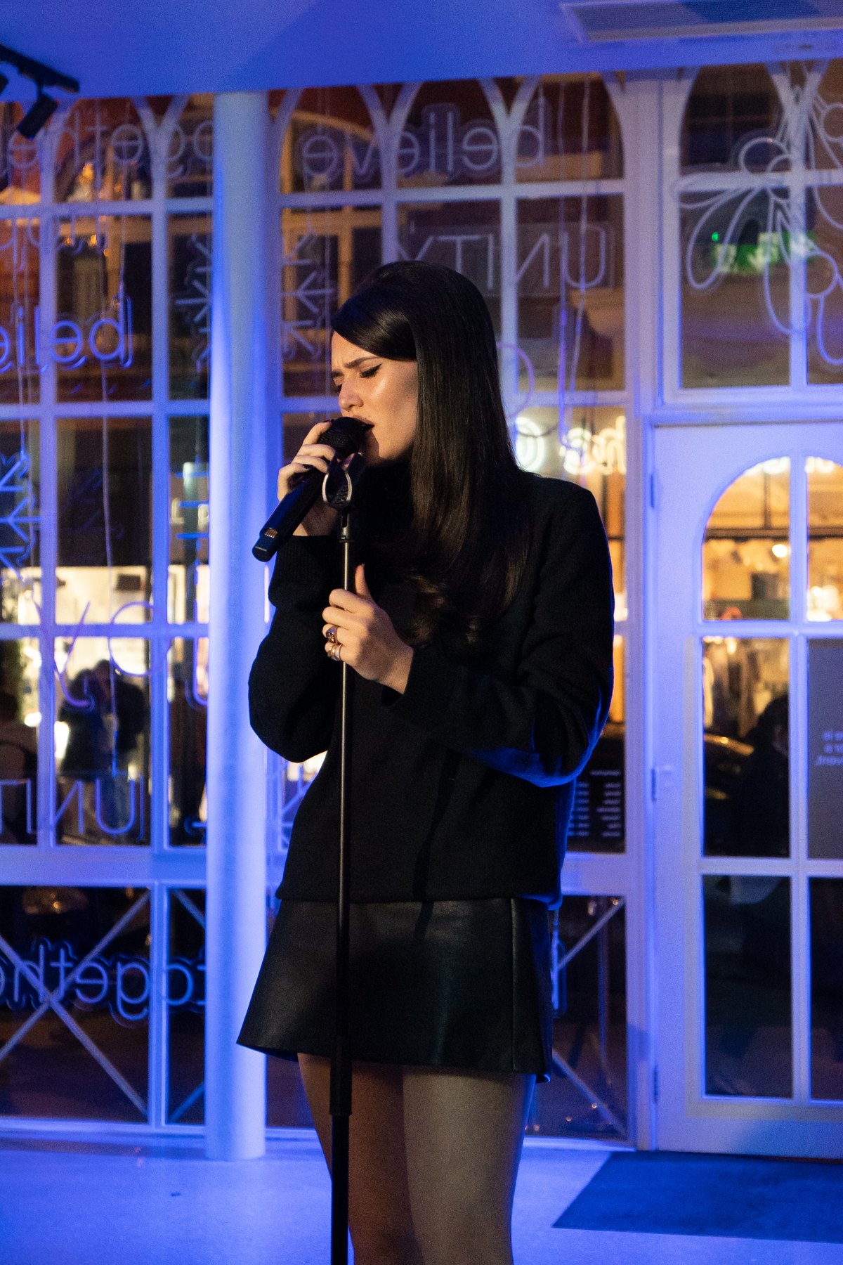 Singer performing into a microphone under blue stage light