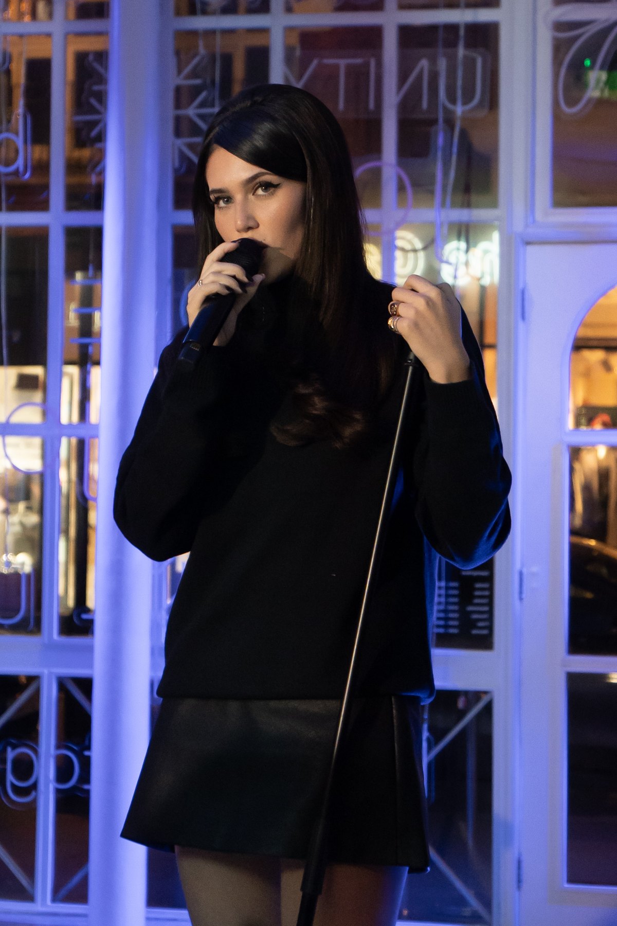 Singer performing with direct gaze under blue and purple lighting
