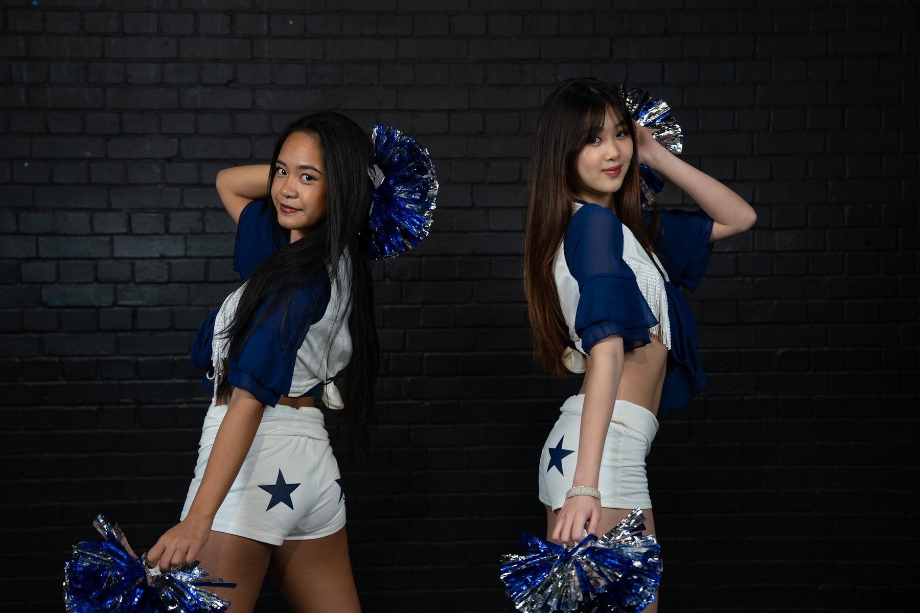 Two friends posing together, pom-poms in hand
