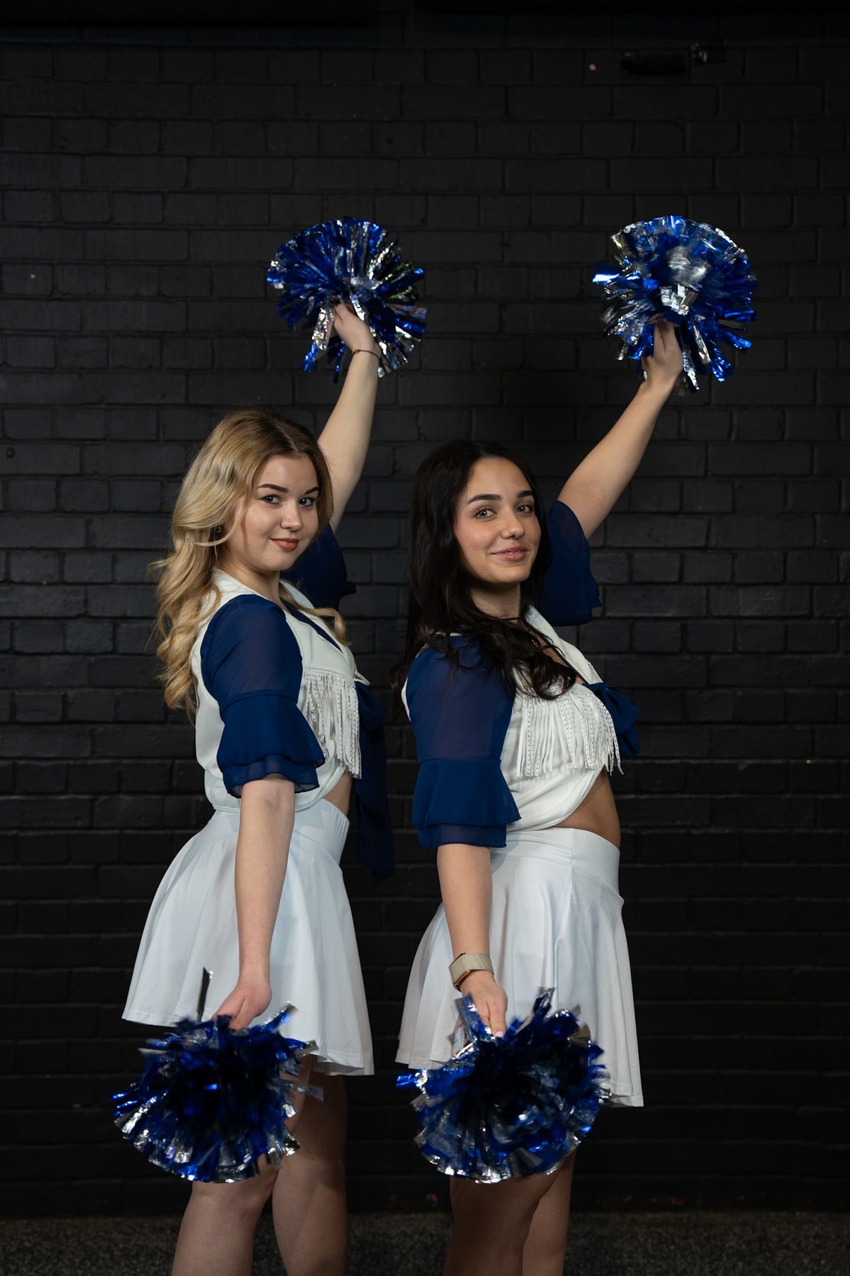 Two friends with pom-poms raised, elegant portrait